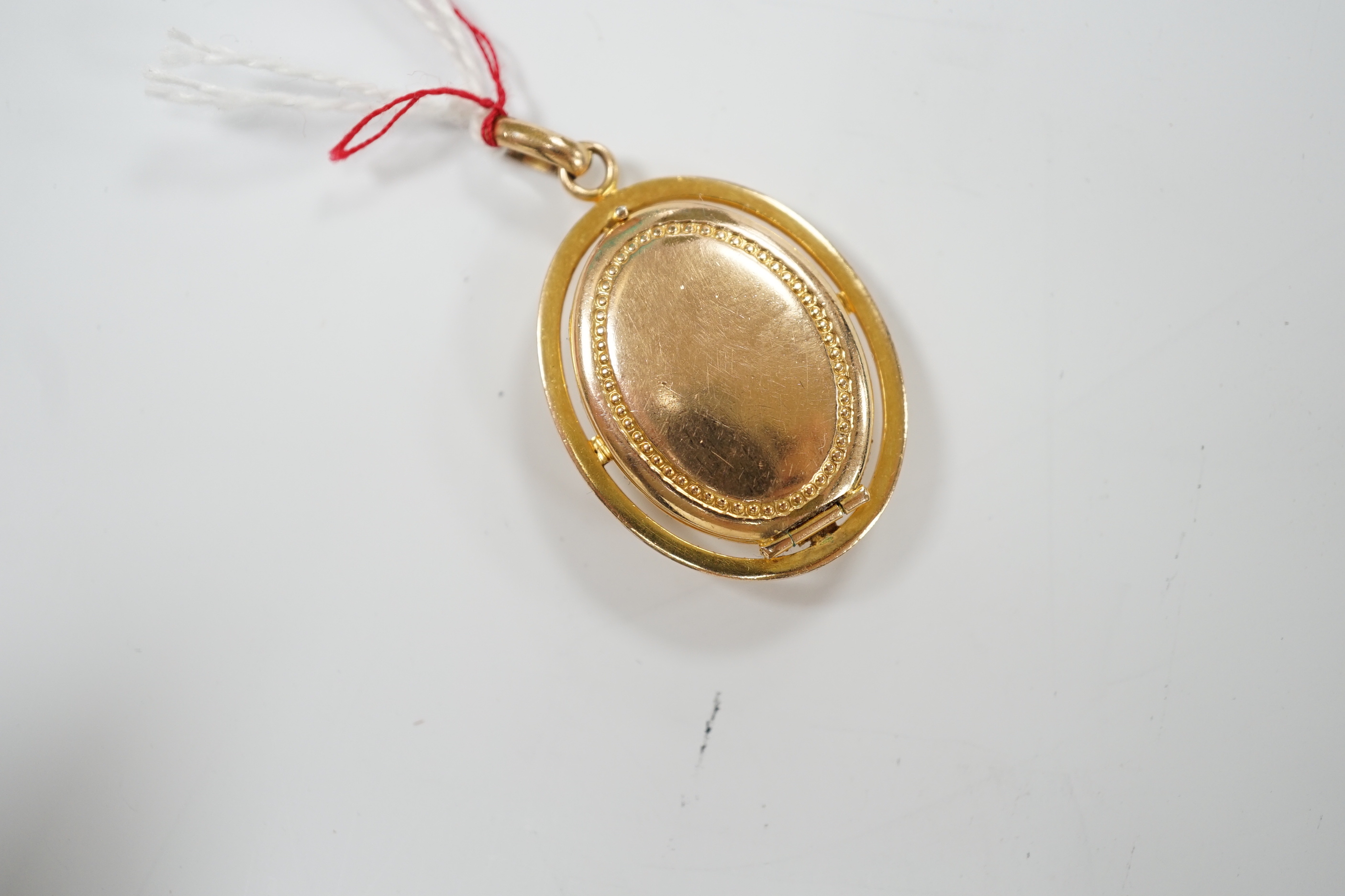 An embossed yellow metal oval pendant locket, 30mm, gross weight 9.6 grams.